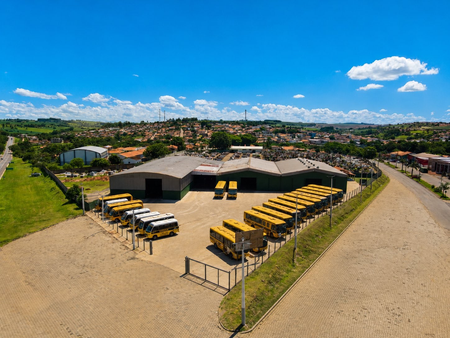 Vista aérea da garagem municipal de Itaberá com dezenas de ônibus escolares estacionados